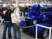 1993 Ford Taurus - Two women stand next to a custom hot rod with a vibrant blue paint job and flame details at an indoor car show.