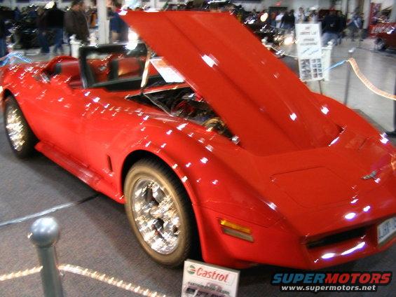 Red convertible with hood open, showing engine. Chrome wheels
