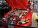 1993 Ford Taurus - A red car with flame decals and a highly customized engine bay is displayed indoors.