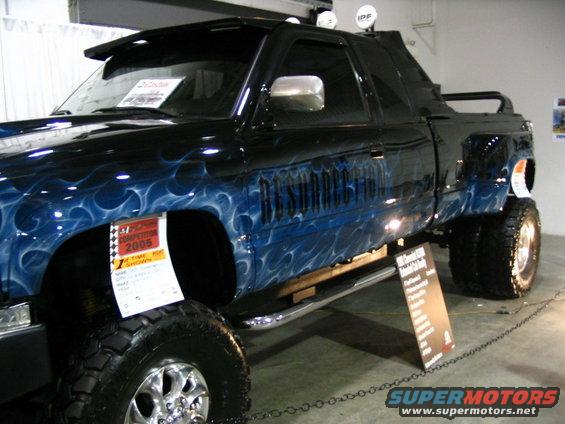 Black pickup truck with blue flame graphics and "RESURRECTION" text on the side. Displayed at an event