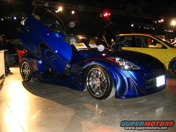 Blue custom car with butterfly doors and custom paint, seen at a car show
