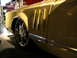 1993 Ford Taurus - A custom yellow car with large chrome rims is displayed indoors.