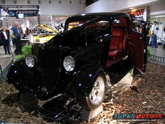 Black hot rod coupe with red interior, open door, on display