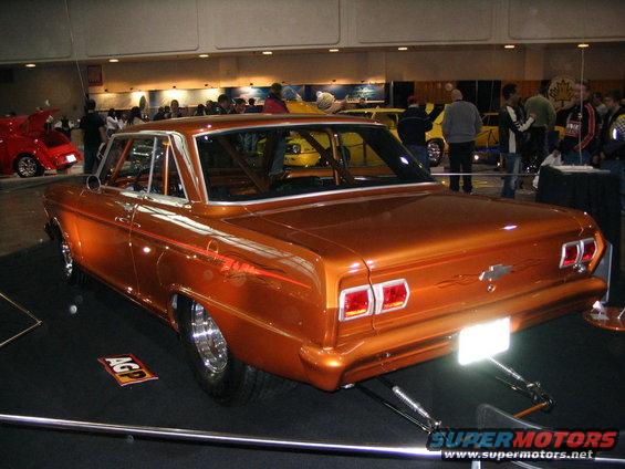 Orange custom car with roll cage, seen from the rear at a car show