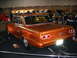1993 Ford Taurus - This customized classic car features a roll cage and a bright orange paint job, displayed indoors.