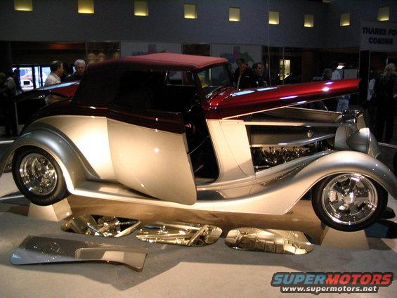 Two-tone silver and maroon custom convertible hot rod with exposed engine and chrome trim pieces on display