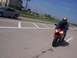 2001 Yamaha R1 - A rider on a red sport motorcycle is on the road, with a car in the background.