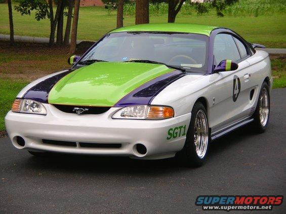 White Ford Mustang with green and purple racing stripes, number 4 on the side, and 'SGT1' on the bumper