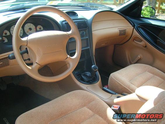 1995 Ford Mustang interior showing tan seats, dashboard, and steering wheel with 'COBRA' emblem