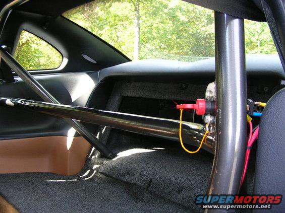 Interior of a 1995 Ford Mustang with a roll cage, tan door panel, and grey carpet