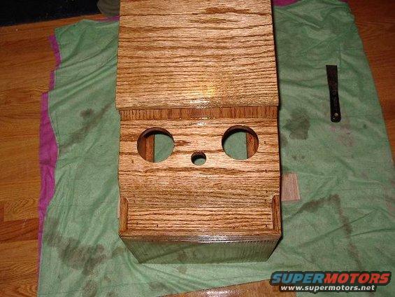 Wooden center console box with two large circular openings and a smaller central hole, resting on a green cloth