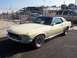2002 Ford Mustang - A classic Mustang is parked in a lot with a fence and buildings in the background.