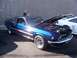 2002 Ford Mustang - A blue 1969 Mustang is displayed with its hood open, revealing the engine bay. A white car is parked nearby.