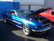 2002 Ford Mustang - A blue 1969 Ford Mustang coupe is displayed with its hood open, alongside another classic Mustang.