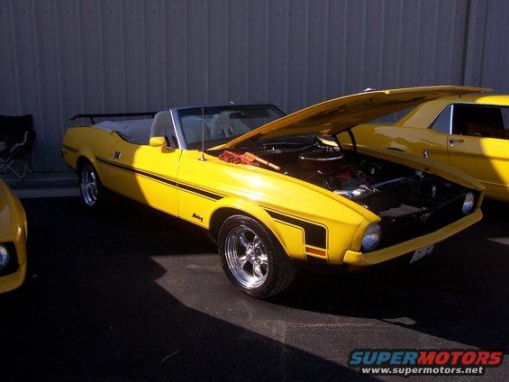Yellow convertible classic car with hood open, parked next to another yellow car