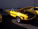 2002 Ford Mustang - A yellow classic convertible with racing stripes and its hood open is displayed outdoors.