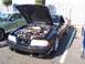 2002 Ford Mustang - Black Ford Mustang with hood open, parked next to a green Mustang. The fender shows '4.6' badging.