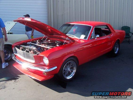 Red 1965 Ford Mustang coupe, hood open, showing engine
