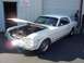 2002 Ford Mustang - Classic white Ford Mustang coupe with hood open, parked outside a building.