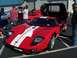 2002 Ford Mustang - A red 2005-2006 Ford GT with white racing stripes is displayed with its doors open at an outdoor event.