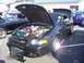 2002 Ford Mustang - A black convertible is displayed with its hood open, revealing the engine and a descriptive sign.