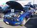 2002 Ford Mustang - A blue 2005 Ford Mustang is displayed with its hood open, revealing engine modifications at a car show.