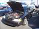 2002 Ford Mustang - A black 2002 Ford Mustang is displayed with its hood open, revealing the engine bay. Another blue Mustang is visible in the background.