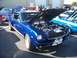 2002 Ford Mustang - A classic blue Mustang is displayed with its hood up, revealing the engine bay. Other vehicles are visible in the background.