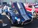 2002 Ford Mustang - A blue Cobra car with its hood open is displayed at an outdoor car show, with other vehicles in the background.