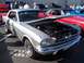 2002 Ford Mustang - A classic silver Ford Mustang is displayed with its hood open at a car show, revealing the engine bay.
