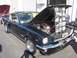 2002 Ford Mustang - A dark green classic Mustang is displayed with its hood open, revealing the engine and a collage of photographs. Another vehicle with its h…