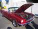 2002 Ford Mustang - A classic red 1965 Ford Mustang convertible is displayed with its hood open, revealing the engine bay.