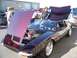 2002 Ford Mustang - A De Tomaso Pantera is displayed with its hood and engine compartment open, attracting attention at an outdoor event.