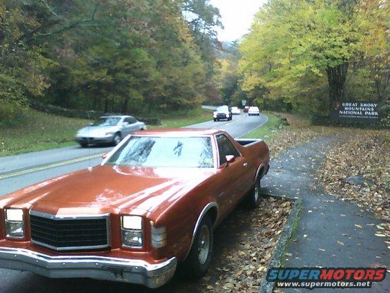 Orange Ford Ranchero parked on roadside with fall foliage and Great Smoky Mountains National Park sign