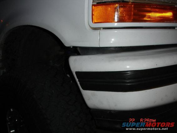 White 1996 Ford Bronco front corner with black bumper trim and orange turn signal