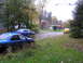 2003 Mazda Protege - A scene with multiple vehicles parked on a wet driveway surrounded by trees with autumn foliage.