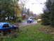 2003 Mazda Protege - Two sedans drive down a residential street during autumn, with fallen leaves on the ground.