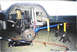 1979 Ford Bronco - The rear suspension of a vehicle is shown undergoing repair, with components removed and supported by tools.