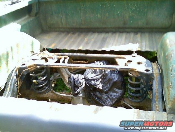 Rear suspension components and black trash bags in the bed of a pickup truck