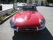 1962 Jaguar XKE - A classic red sports car is parked on a street, showing its distinctive front end and headlights.