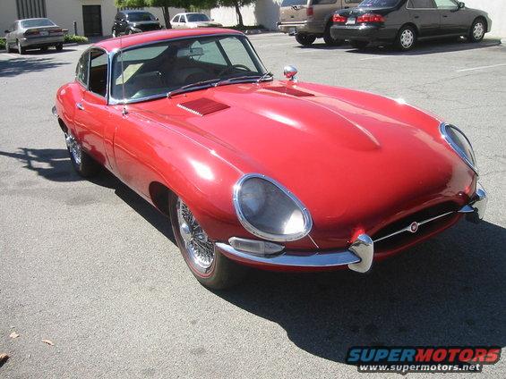 Red coupe with wire wheels, chrome bumpers, and hood vents