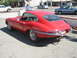1962 Jaguar XKE - A red coupe with distinctive E-Type body style and wire wheels is parked on asphalt.