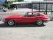 1962 Jaguar XKE - A red 1962 Jaguar XKE coupe is parked on a street, viewed from the side.