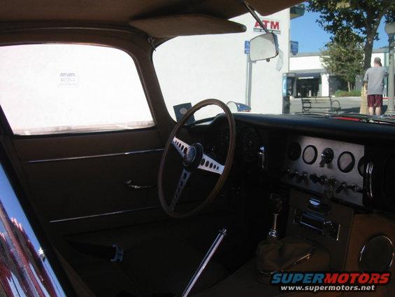 Interior view of a 1962 Jaguar XKE showing the steering wheel, dashboard gauges, and gear shifter