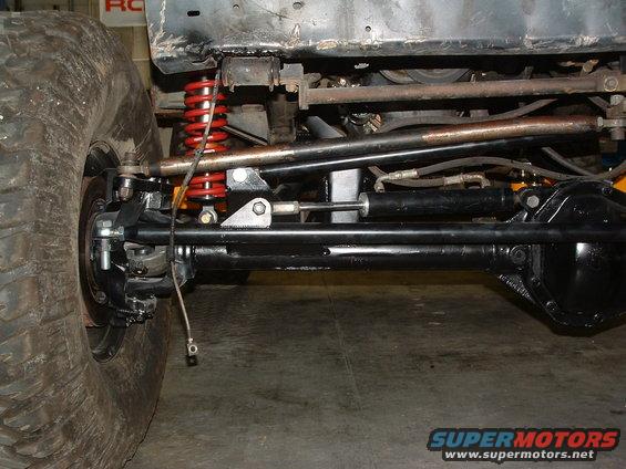 Jeep suspension with red coil springs, black differential, and large tire