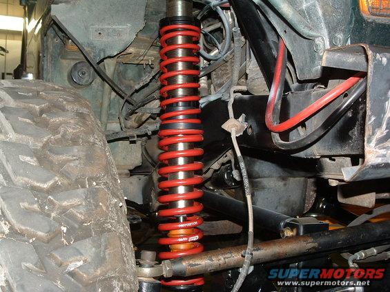 Close-up of a red coilover shock absorber and large tire on a vehicle