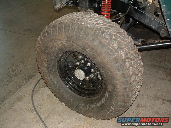 Close-up of a large off-road tire with a red shock absorber visible above it