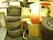 1985 Suzuki QUADRUNNER 250/LT250 - Various vehicle parts and tires are stored in a cluttered garage or workshop area.