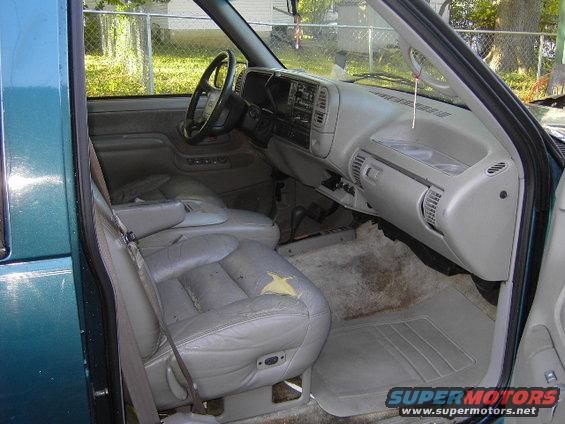 Teal 1995 GMC Suburban interior, driver's side, showing torn leather seat, dashboard, and steering wheel