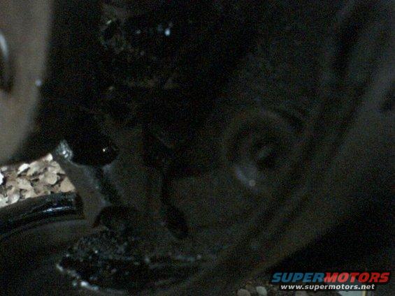 Undercarriage of a dark vehicle with gravel visible